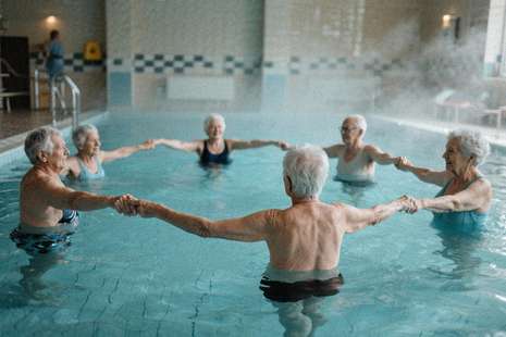 Grup de seniori participând la o sesiune de gimnastică acvatică într-un bazin termal